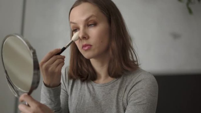 女人拿着化妆刷在脸上化妆