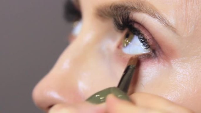 在美容院中，专业美容师将眼线涂在女孩眼睛的下眼睑上。专业化妆师用柔软薄眼妆刷特写视频