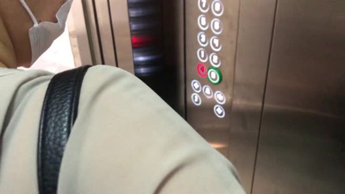 女人在电梯上按下按钮后用消毒剂消毒手