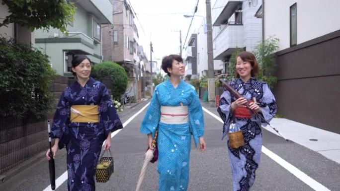 日本女性朋友在浴衣走在住宅区的街道上