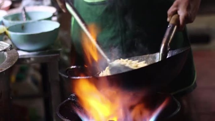 泰国曼谷约瓦拉吉路街头美食厨师在黑锅里用火做饭