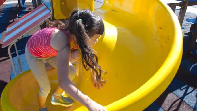 两个五岁和八岁的小漂亮姐妹在海洋主题游乐场玩得开心。女孩们在阳光明媚的夏日爬上黄色的塑料滑梯。50 