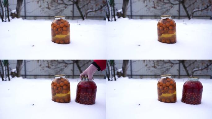 街上雪中水果罐头果汁特写。冬季在花园里密封的蜜饯罐