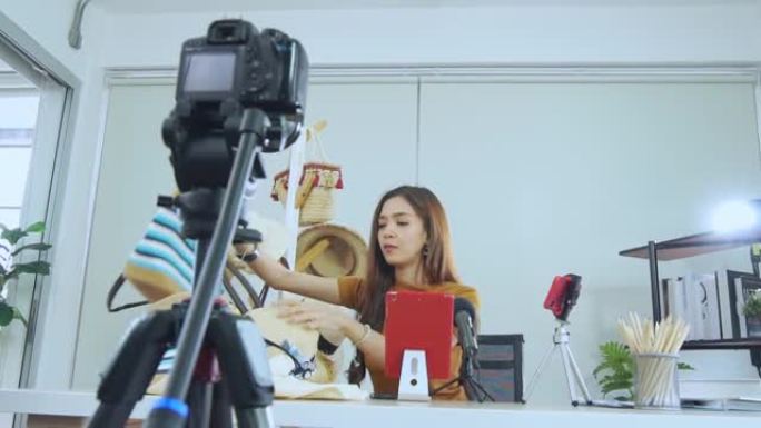 年轻的亚洲女性博主录制vlog视频，影响者在社交媒体上直播服装在线购物