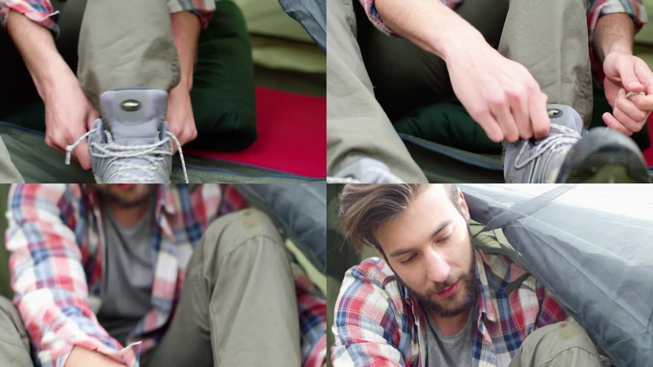 年轻人徒步旅行后系鞋带的特写镜头。漂亮的男人在帐篷里放松。露营激情