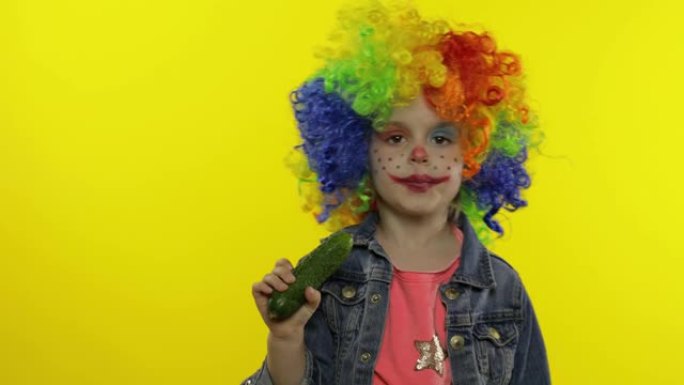 彩虹假发中的小女孩小丑做着傻脸，唱歌，微笑，跳舞。万圣节