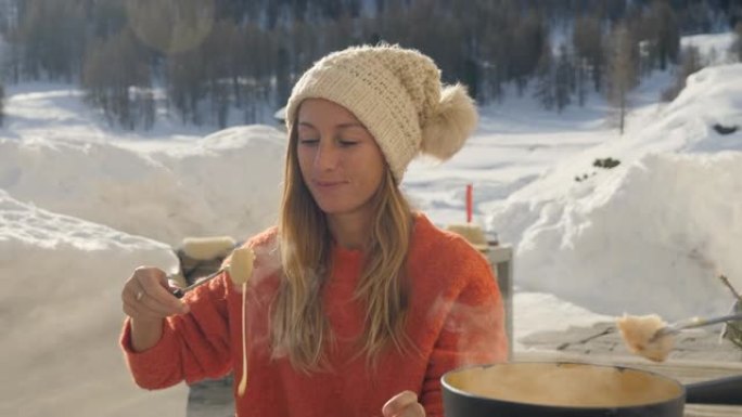 冬天，成熟的男人和年轻的女人在瑞士阿尔卑斯山分享奶酪火锅，一家人一起用餐，雪山滑雪假期。两人吃户外慢
