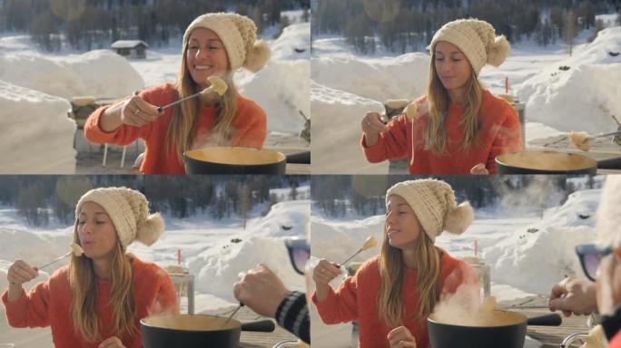 冬天，成熟的男人和年轻的女人在瑞士阿尔卑斯山分享奶酪火锅，一家人一起用餐，雪山滑雪假期。两人吃户外慢