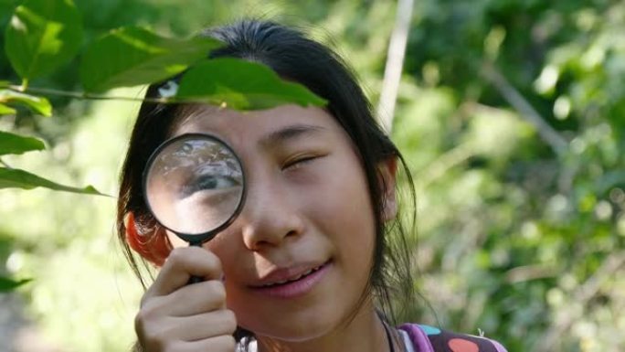 亚洲女孩在户外探险期间使用放大镜进入森林自然保护区。