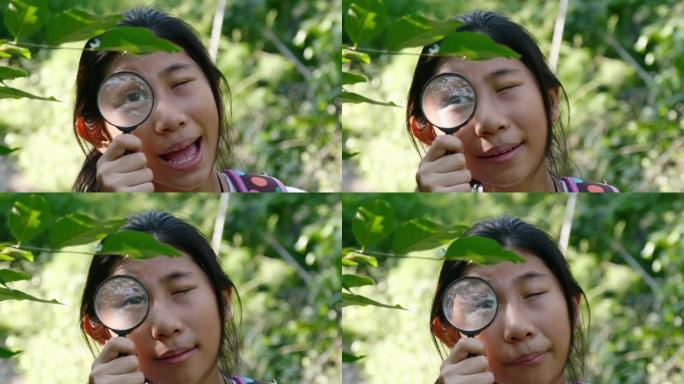 亚洲女孩在户外探险期间使用放大镜进入森林自然保护区。