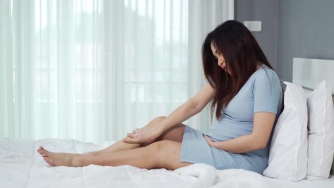 孕妇在床上按摩腿部，肌肉疼痛，扭伤或抽筋疼痛