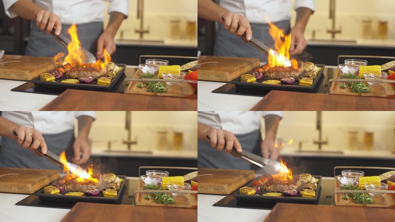 在烧烤的现代厨房烹饪蔬菜牛排。男厨师在餐厅准备火烧烤盘。煎锅里的火焰。做美味的食物。在菜肴上加工餐点