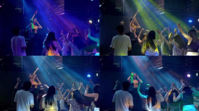 女子DJ在音乐会派对上跳舞，效果轻盈。年轻人在俱乐部跳舞。夜生活派对和带灯光效果的迪斯科概念。