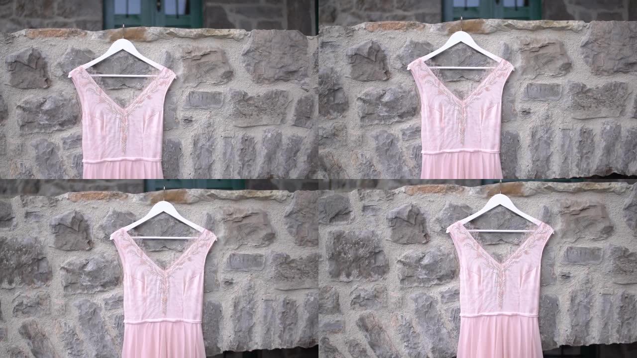 淡粉色婚纱的串珠紧身胸衣挂在石墙上，特写
