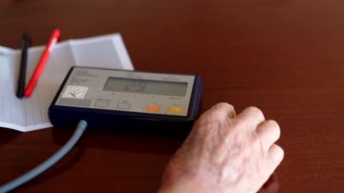 老人皱巴巴的手的特写打开眼压计，用于在生病期间在家中测量血压和脉搏，退休的人每天照顾自己并检查健康