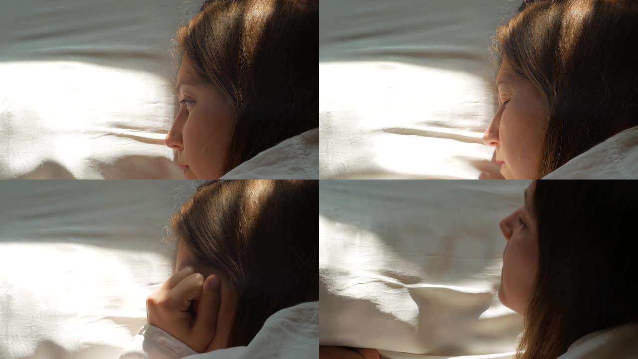 平静的年轻女子睡在舒适舒适的床上，躺在白色柔软的枕头上，早上醒来。宁静的女孩躺在床上睡觉，享受健康的