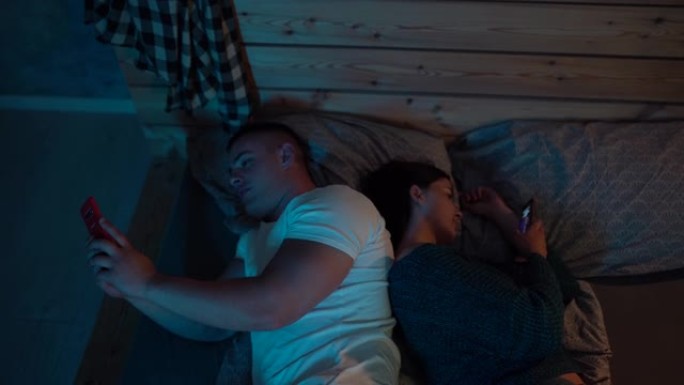 夫妇躺在床上使用智能手机