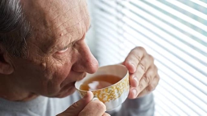 一位老人喝茶，看着窗外