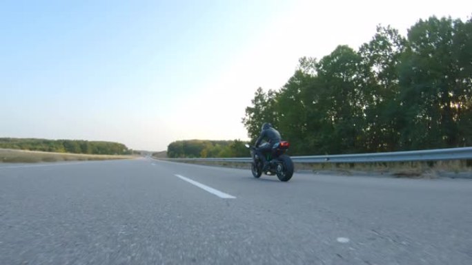 跟随戴头盔的摩托车手在高速公路上骑运动摩托车。男子在秋天的乡间小路上骑摩托车。旅途中开车的人。自由和
