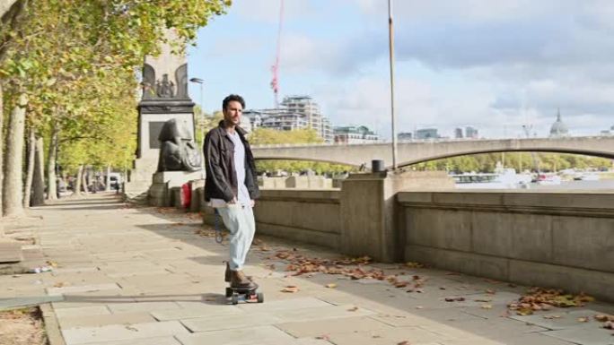 沿着泰晤士河堤岸玩滑板的休闲英国男性