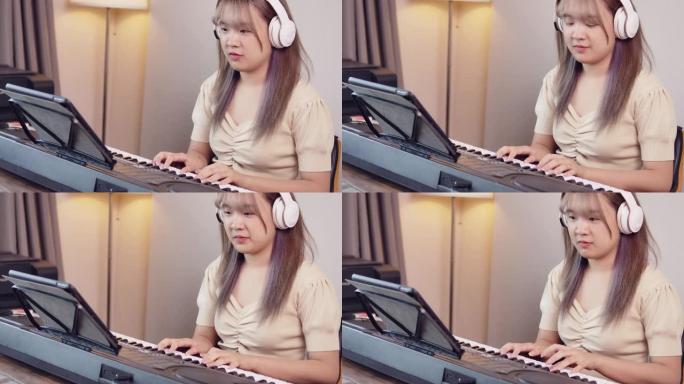 一个年轻的长发美丽的亚洲女孩少年正在她的房间日场景中用耳机练习钢琴键盘音乐。