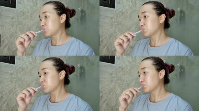 亚洲女性挤牙膏在浴室刷牙
