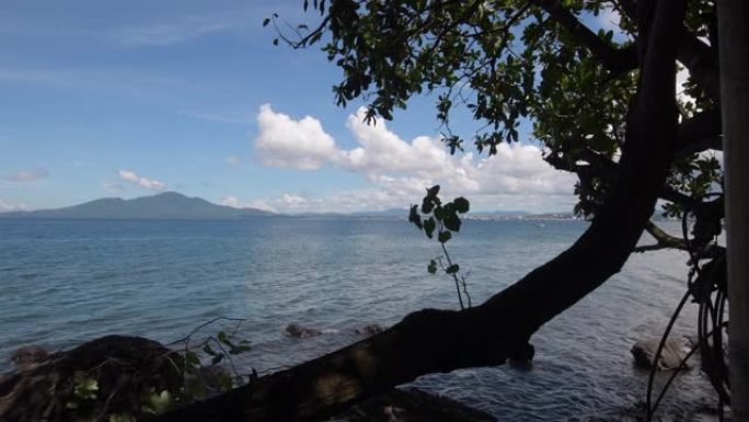 海景。万鸦老市的摩天大楼和山丘背景下的Malalayang海滩的白天景色