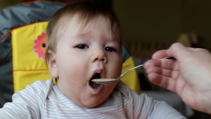 用勺子喂小帅哥粥，特写。一岁左右儿童营养，背景，高加索人
