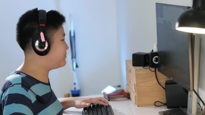 快乐的亚洲男孩在家用电脑玩网络游戏，生活方式概念。