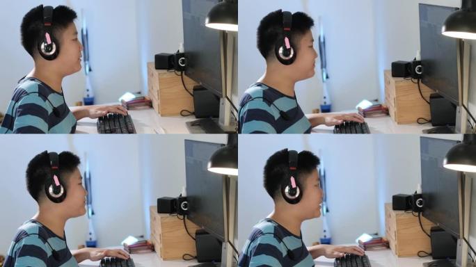 快乐的亚洲男孩在家用电脑玩网络游戏，生活方式概念。