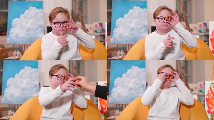 小男孩玩小百吉饼，把圆饼放在眼镜上。视力。