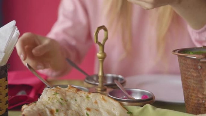 一位年轻的白人妇女在餐馆里享用印度菜。印度食品概念