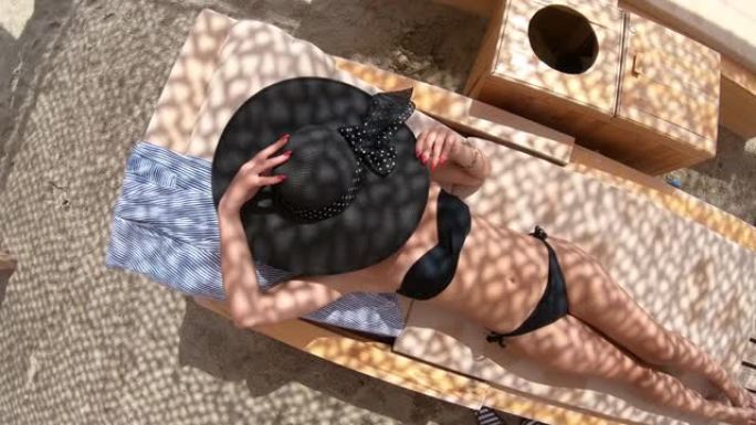 穿着比基尼和帽子的性感女孩躺在豪华海滩度假胜地放松
