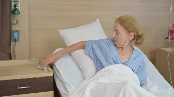 老年女性患者在医院的床上按下紧急护士呼叫按钮