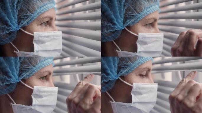 悲伤的病人，过度劳累的严肃的女医护人员看着窗户。肖像医生护士戴着防护口罩，新型冠状病毒肺炎预防传染性