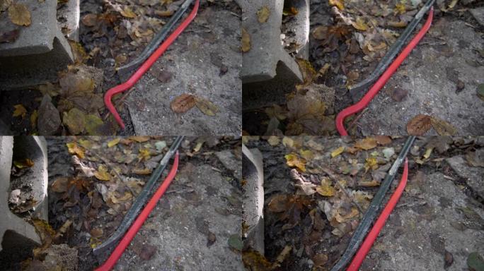 红色和黑色的撬棍躺在肮脏的土地上，秋天的叶子