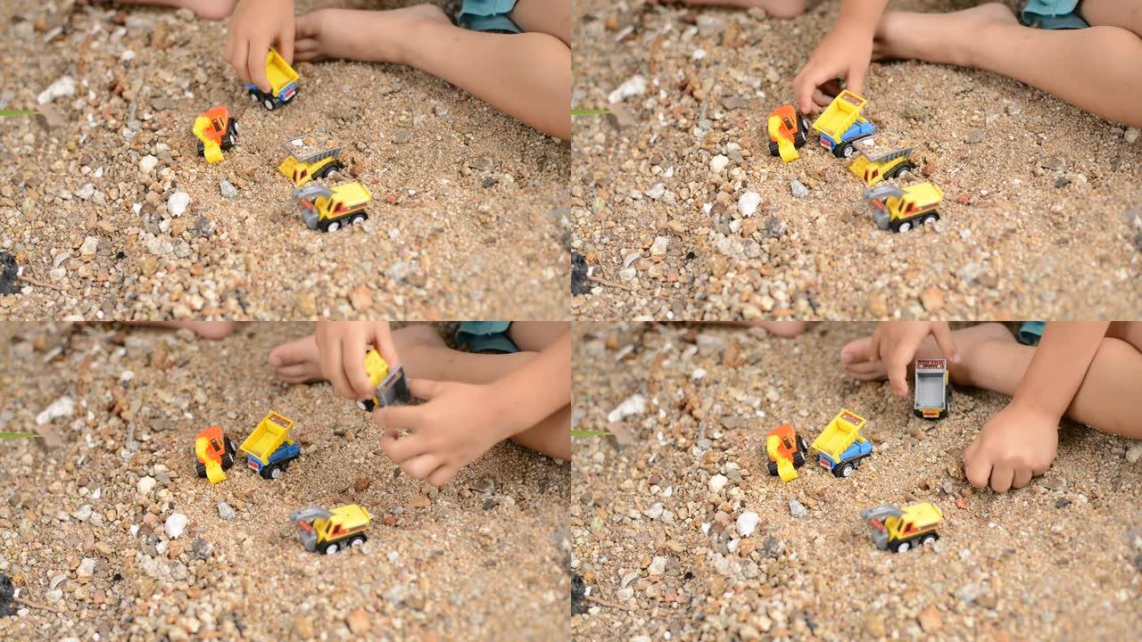 小男孩在沙滩上玩塑料玩具挖掘机