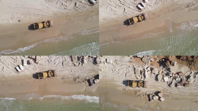 重型机械的鸟瞰图，铲子在海滩上工作的岩石和砾石，推土机在海皮上工作的岩石，重型设备自上而下的镜头
