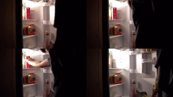 一名男子晚上打开冰箱，拿了一盒牛奶