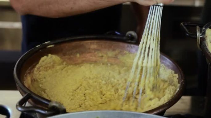 在铜质杯中搅拌和混合一种称为玉米粥的传统食品