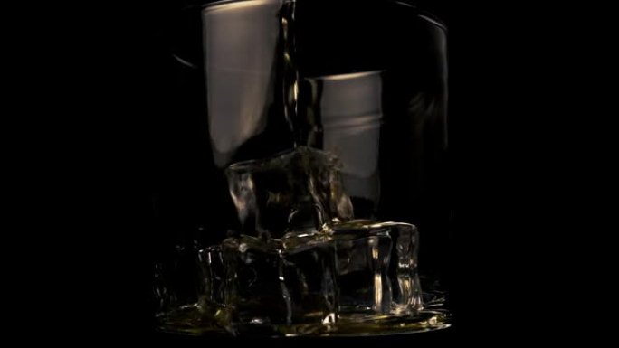 将金色威士忌倒入带有黑色背景上的冰块的玻璃杯中。细流