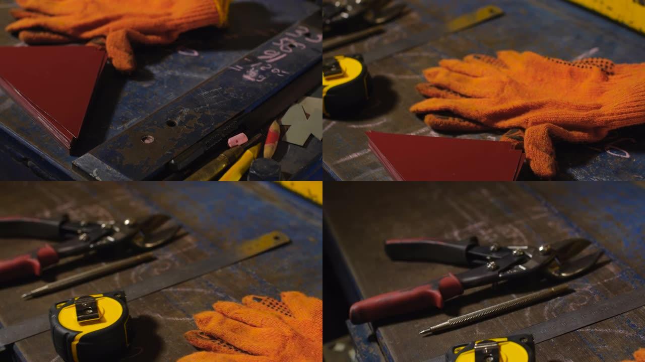 金属桌子上工程工具的跟踪镜头。防护手套、卷尺、铅笔、金属剪刀和金属片。在制造锡制品的车间工作