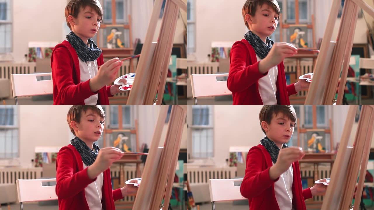 青少年手握画笔调色板，蘸油漆。使用画架绘图