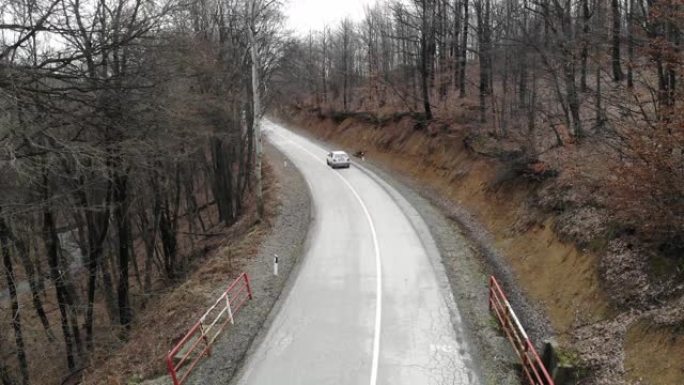 在穿过秋天森林的道路上，从上方看无人机。空中汽车在秋天穿越森林