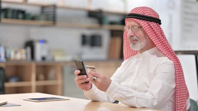 老阿拉伯商人在智能手机上进行在线支付