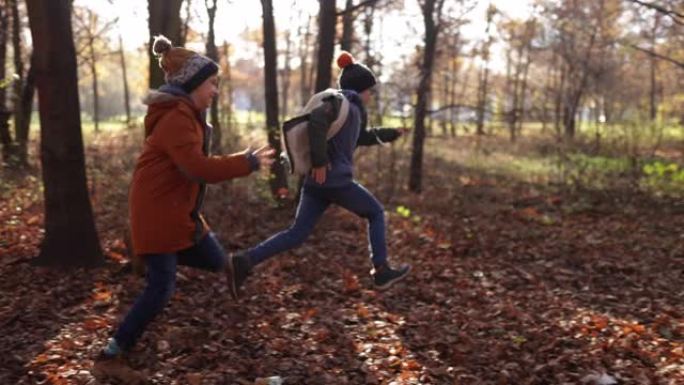 两个男孩在秋天的森林中奔跑