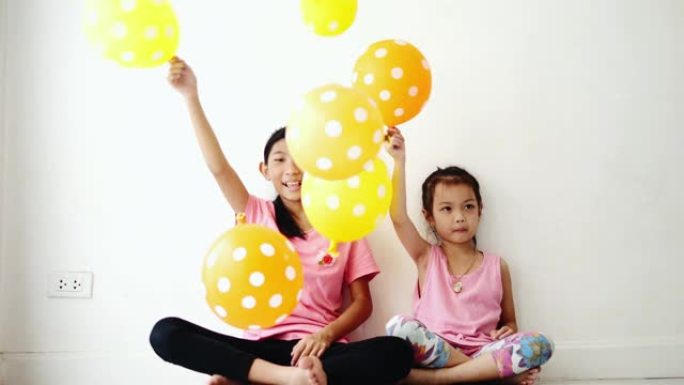 亚洲女孩在家一起在地板上举起气球，为家居装修概念做准备。