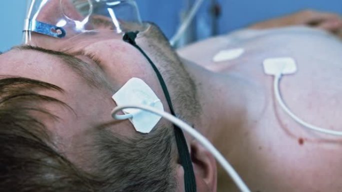 男性患者在医院呼吸氧气支持，心率机旁边。