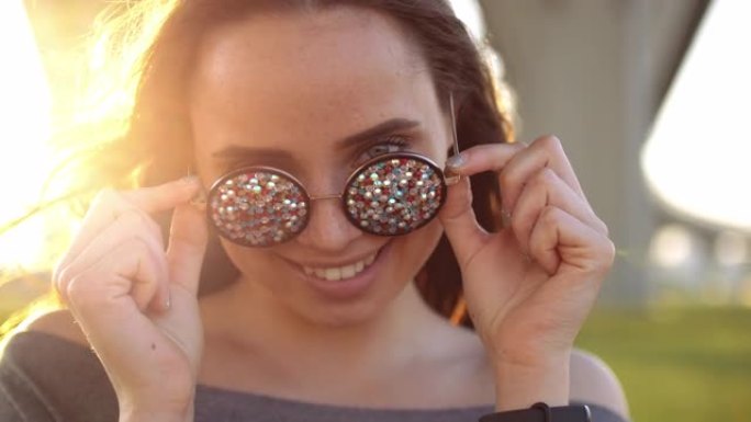 年轻女游客笑着和开心的肖像近距离特写。女学生在城市街头，时尚肖像与酷太阳镜。迪斯科太阳镜粘贴。