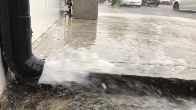 近距离的水从排水管倒入街道。一条强大的溪流涌上道路。秋雨。